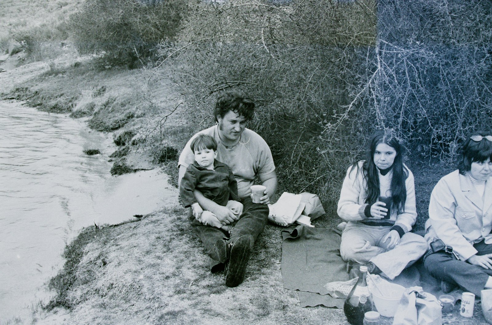 A group picnicking on the bank of a river